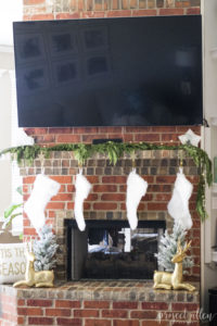 Brick Christmas fireplace with styled mantle and faux gold reindeer.