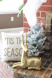 Brick Christmas fireplace with styled mantle and faux gold reindeer.