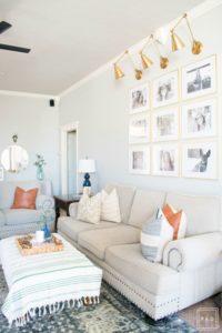 Welcome to our Spring Home Tour: See how we transformed our home with just a few simple changes, a brass frame gallery wall with gold swing arm sconces frame this neutral sofa adorned with mudcloth and leather pillows.