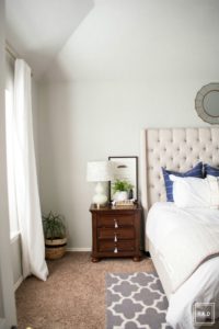 Welcome to our Spring Home Tour: See how we transformed our home with just a few simple changes, a modern farmhouse master bedroom with white curtains, white bedding, dark nightstand with white gourd lamp and greenery.