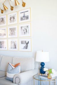 Welcome to our Spring Home Tour: See how we transformed our home with just a few simple changes, a brass frame gallery wall with brass swing arm sconces frame this neutral sofa adorned with mudcloth and leather pillows. Blue gourd lamp and brass glass table create a cozy vignette.