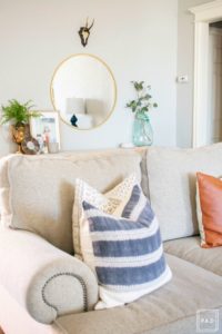 Welcome to our Spring Home Tour: See how we transformed our home with just a few simple changes, neutral sofa adorned with mudcloth and leather pillows, console table with framed art prints and round brass mirror.