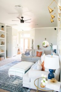 Welcome to our Spring Home Tour: See how we transformed our home with just a few simple changes, a brass frame gallery wall with gold swing arm sconces frame this neutral sofa adorned with mudcloth and leather pillows and black modern ceiling fan.