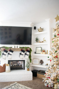 A snowy flocked Christmas tree decorated in red, green and gold gives a big dose of nostalgia to this modern farmhouse living room.