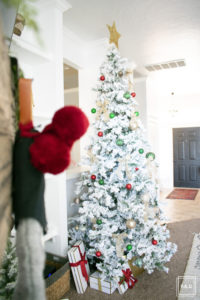 A flocked Christmas tree decorated in red, green and gold gives a big dose of nostalgia to this modern farmhouse living room.