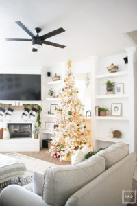 A snowy flocked Christmas tree decorated in red, green and gold gives a big dose of nostalgia to this modern farmhouse living room.