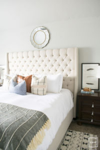 breath of fresh air spring home tour: California cool master bedroom complete with a tufted grand headboard, pattern mixed pillows and tribal rug.