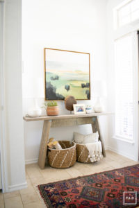 breath of fresh air spring home tour: Modern entryway with vintage rug, target artwork, wicker baskets and birch logs against white walls.