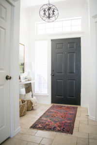 breath of fresh air spring home tour: Modern entryway with vintage rug, target artwork, wicker baskets and birch logs against white walls.