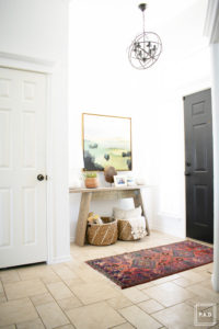 breath of fresh air spring home tour: Modern entryway with vintage rug, target artwork, wicker baskets and birch logs against white walls.